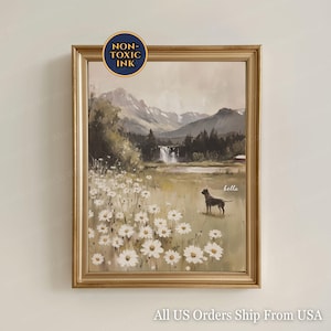 Pode incluir: Pintura de paisagem emoldurada em uma moldura dourada, apresentando um campo de margaridas brancas, um cachorro e uma cachoeira contra um cenário de montanhas. A pintura tem as palavras "Non-Toxic Ink" em um círculo no topo.