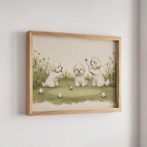 以下が含まれることがあります： ゴルフコースにいる3匹のふわふわした白い子犬が描かれた額入りアートプリント。1匹の子犬はゴルフクラブを持ち、もう1匹は中央に座り、3匹目は背の高い草の近くでクラブを持っています。緑の芝生の上には3つの白いゴルフボールが散らばっています。