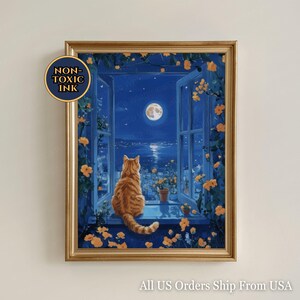 May include: A framed print shows a ginger cat looking out of a window at a full moon over a cityscape. The window is decorated with yellow flowers and greenery. The print has a gold frame and the text "NON-TOXIC INK".