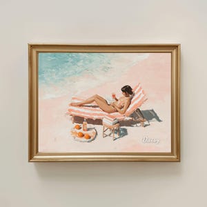 May include: A framed painting of a beach scene. A person is relaxing on a striped deckchair, reading a book and holding a drink. Oranges and a bottle are on a small table. The painting is signed "Daisy".