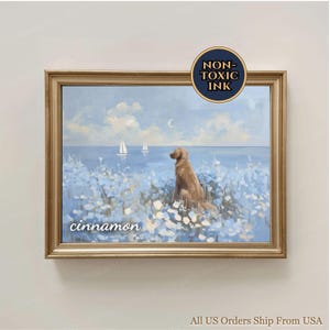 May include: A framed painting depicting a golden retriever in a field of blue flowers, looking out at sailboats on the sea under a cloudy sky. The painting is in a gold frame, with the word "cinnamon" written on the bottom left.