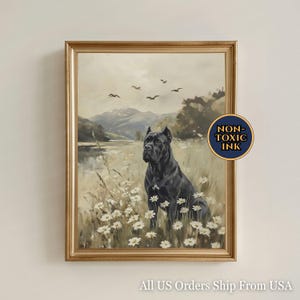 May include: Framed artwork featuring a black dog in a field of white flowers, with a lake and mountains in the background. The painting has a gold frame and a "Non-Toxic Ink" sticker. The artwork is a landscape painting.