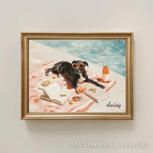 Può includere: Stampa artistica incorniciata raffigurante un cane nero con occhiali da sole arancioni, che si rilassa a bordo piscina. Il cane è su un asciugamano rosa con un libro, un bicchiere di vino e una bottiglia. L'opera d'arte ha una cornice dorata.