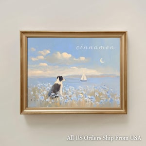 May include: A framed painting depicting a black and white dog in a field of blue flowers, with a sailboat on the water. The sky is light blue with clouds and a crescent moon. The word "cinnamon" is written in cursive.