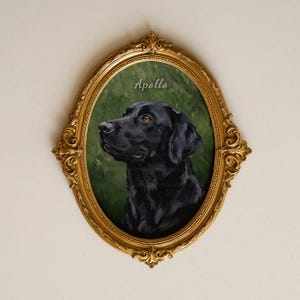 Puede incluir: Un retrato ovalado de un Labrador retriever negro sobre un fondo verde oscuro, con el nombre Apollo en letra blanca sobre el perro. La obra está encerrada en un marco dorado metálico ornamentado con detalles de volutas intrincadas.