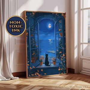 Könnte beinhalten: Gerahmter Kunstdruck, der eine schwarze Katze in einem Fenster zeigt, die eine mondbeschienene Meereslandschaft betrachtet. Das Kunstwerk hat einen goldenen Rahmen, eine blaue Farbpalette und den Text "NON-TOXIC INK".