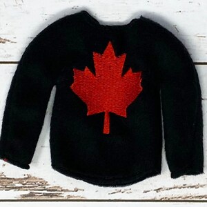 Puede incluir: Camiseta negra de manga larga con un diseño de hoja de arce roja.