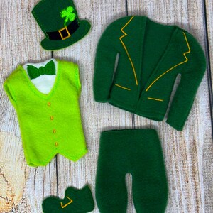 Peut inclure: Un ensemble de la Saint-Patrick en feutre, comprenant une veste verte avec des bordures jaunes, un pantalon vert, un gilet avec un nœud papillon, un chapeau avec un trèfle et une chaussure. L'ensemble est en feutre vert.