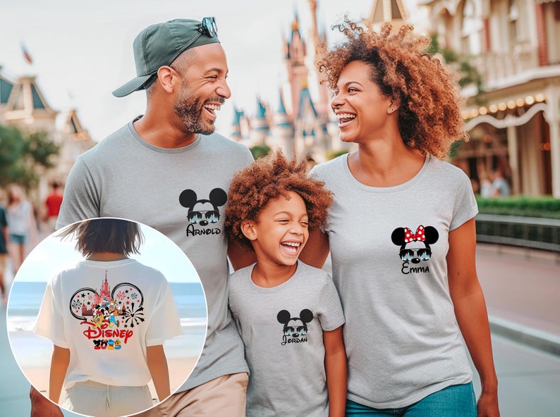 Pu&ograve; includere: Una famiglia indossa magliette grigie abbinate con disegni di Topolino e Minnie. Le magliette presentano nomi personalizzati e un design Disney 2023 sul retro di una maglietta. La famiglia sorride davanti a un parco a tema.