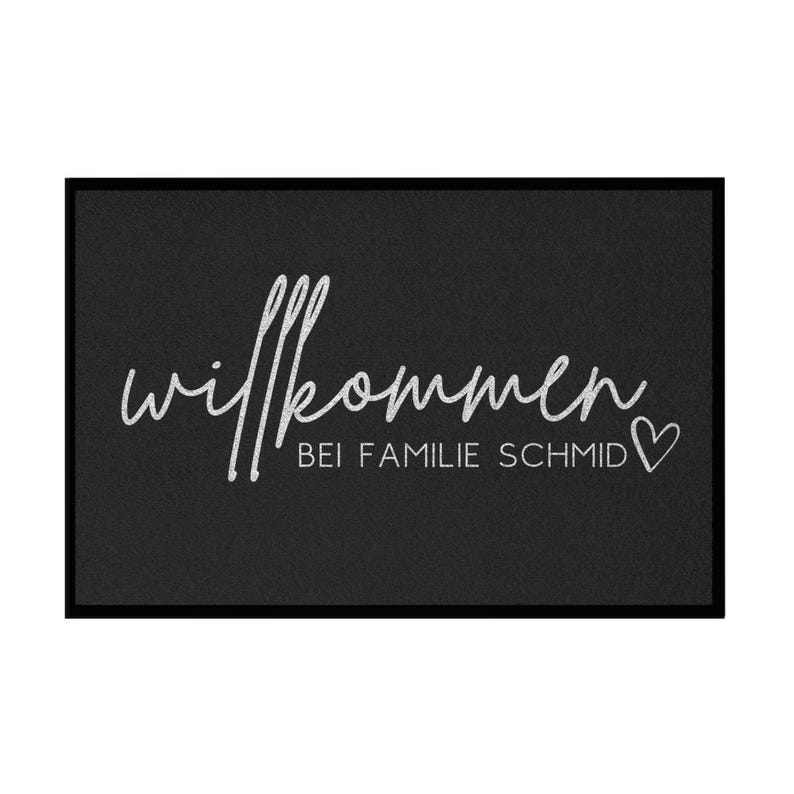 Peut inclure: Paillasson d'accueil noir avec du texte blanc qui dit "Willkommen bei Familie Schmid" avec un petit c&oelig;ur.