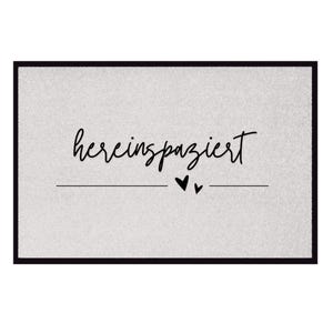 May include: A gray doormat with black text that says "herein spaziert" with two small black hearts underneath the text.