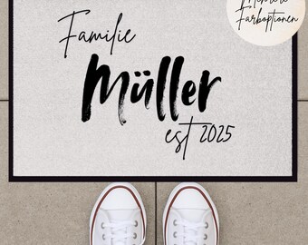 Könnte beinhalten: Eine weiße Fußmatte mit schwarzem Text, der "Familie Müller est 2025" lautet.