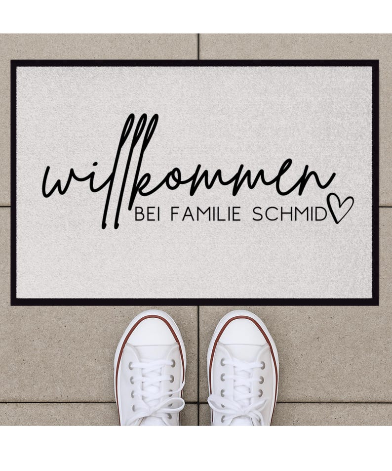 Peut inclure: Un paillasson blanc avec du texte noir qui dit "Willkommen bei Familie Schmid" avec un symbole de c&oelig;ur.