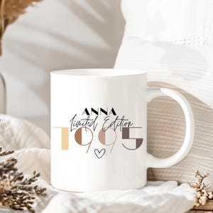 May include: White ceramic mug with a black and white design that says "Anna Limited Edition 1995" with a small heart in the center. The numbers are in different colors and shapes.