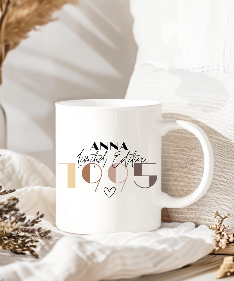 May include: White ceramic mug with a black and white design that says "Anna Limited Edition 1995" with a small heart in the center. The numbers are in different colors and shapes.