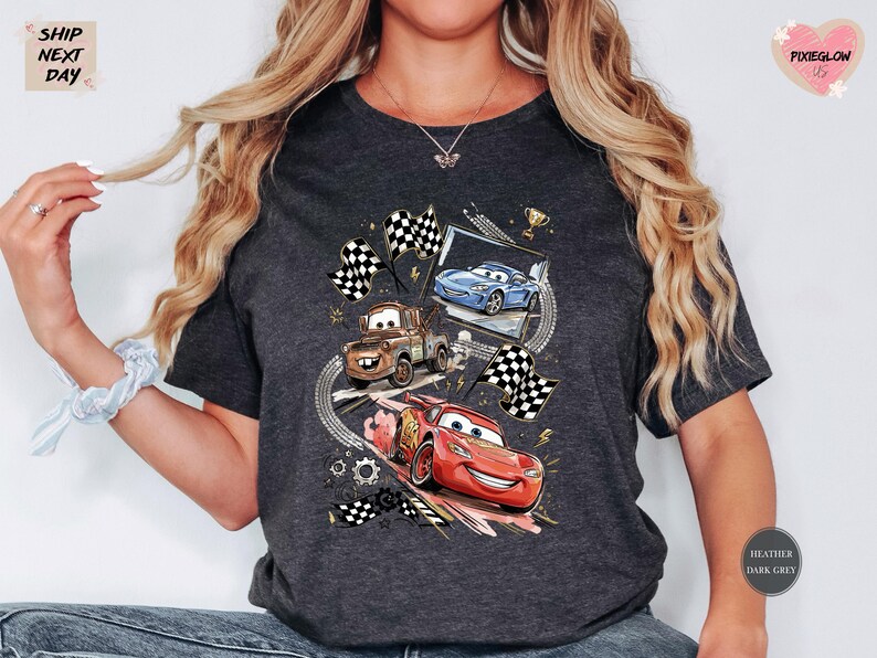 A person wearing a gray t-shirt with a graphic design featuring characters from the animated movie Cars.