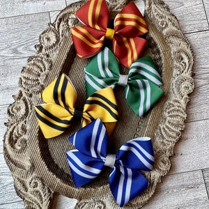 May include: Four hair bows with striped patterns in the colors of the Hogwarts houses: Gryffindor (red and gold), Slytherin (green and silver), Hufflepuff (yellow and black), and Ravenclaw (blue and bronze).