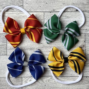 May include: Four different colored hair bows with a white elastic headband. The bows are made of fabric with stripes in the colors of the Hogwarts houses: Gryffindor (red and gold), Slytherin (green and silver), Ravenclaw (blue and bronze), and Hufflepuff (yellow and black).