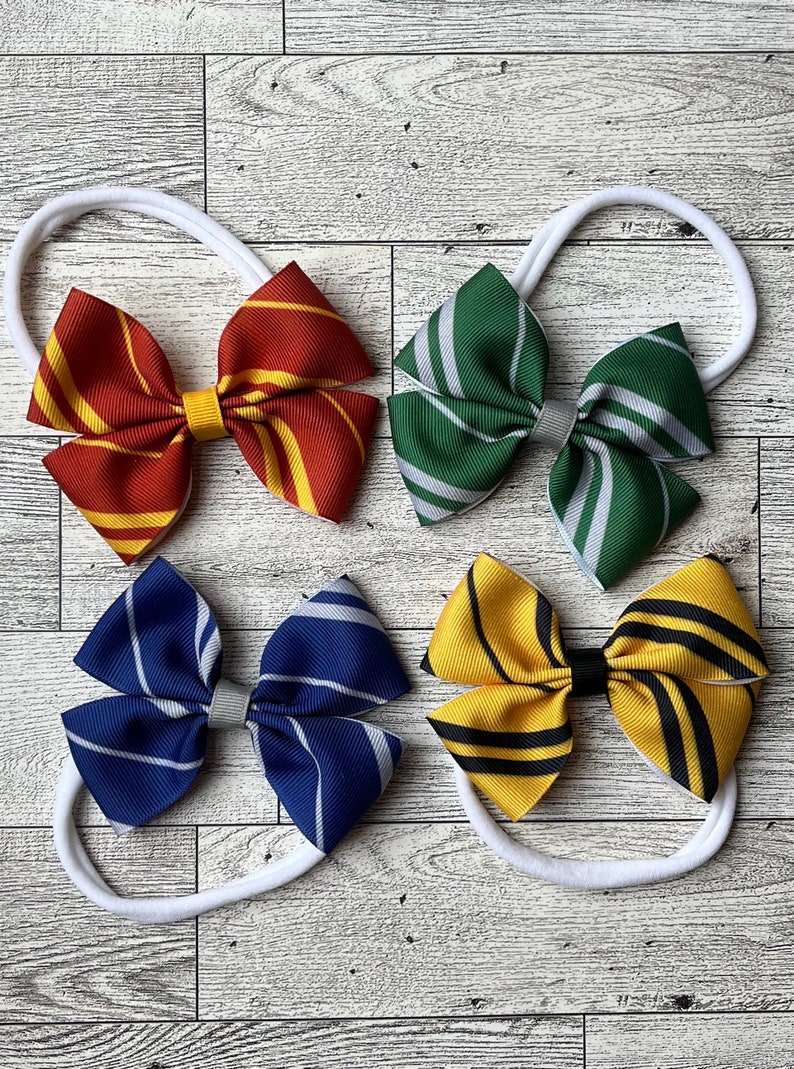 May include: Four different colored hair bows with a white elastic headband. The bows are made of fabric with stripes in the colors of the Hogwarts houses: Gryffindor (red and gold), Slytherin (green and silver), Ravenclaw (blue and bronze), and Hufflepuff (yellow and black).