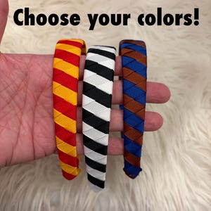 May include: Three braided headbands in red and yellow, black and white, and blue and brown. The text "Choose your colors!" is displayed above the headbands.