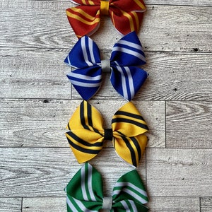 May include: Four hair bows in the colors of the Hogwarts houses: Gryffindor (red and gold), Ravenclaw (blue and silver), Hufflepuff (yellow and black), and Slytherin (green and silver).