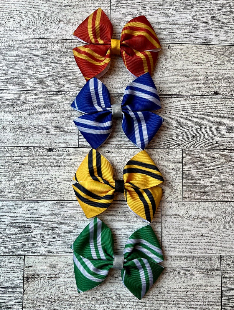 May include: Four hair bows in the colors of the Hogwarts houses: Gryffindor (red and gold), Ravenclaw (blue and silver), Hufflepuff (yellow and black), and Slytherin (green and silver).