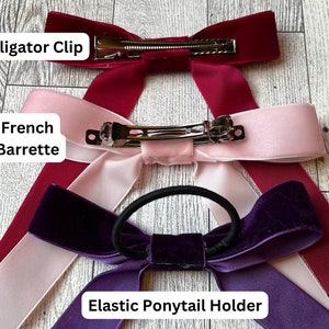 May include: Three velvet ribbon hair bows with different fasteners: an alligator clip, a French barrette, and an elastic ponytail holder. The bows are in burgundy, pink, and purple.