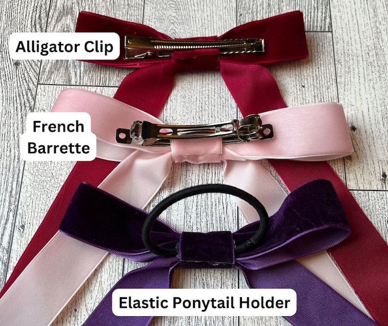 May include: Three velvet ribbon hair bows with different fasteners: an alligator clip, a French barrette, and an elastic ponytail holder. The bows are in burgundy, pink, and purple.