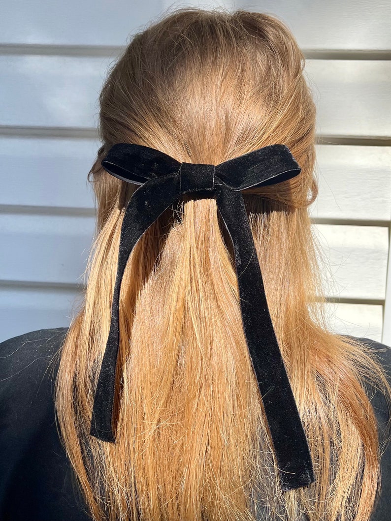 May include: A black velvet ribbon tied in a bow, used as a hair accessory.