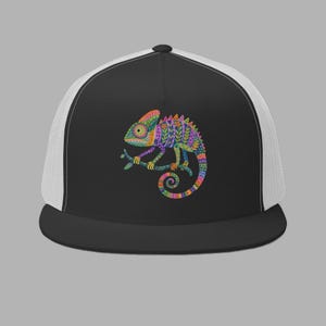 Pode incluir: Um boné trucker preto e branco com um gráfico colorido e estampado de um camaleão no painel frontal. O boné tem uma frente preta sólida, uma aba reta e painéis laterais e traseiros de rede branca. O design do camaleão inclui laranja, roxo, azul e verde.