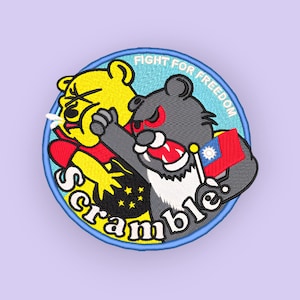 May include: Embroidered patch featuring two cartoon bears in a fight. One bear is yellow, the other is gray, and they are set against a light blue background. The patch has the words "Fight for Freedom" and "Scramble."