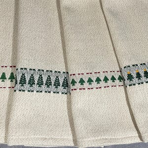 May include: Four cream-colored kitchen towels with embroidered green Christmas trees and red or gold stitching.