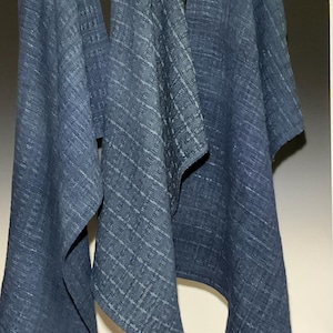 Pode incluir: Três toalhas de cozinha azuis penduradas em uma haste de madeira. As toalhas têm um padrão tecido texturizado.