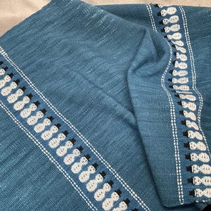May include: A blue woven throw blanket with white and black snowman designs on the border.
