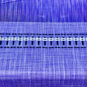 May include: Close-up of a blue woven fabric with a white and black patterned border.