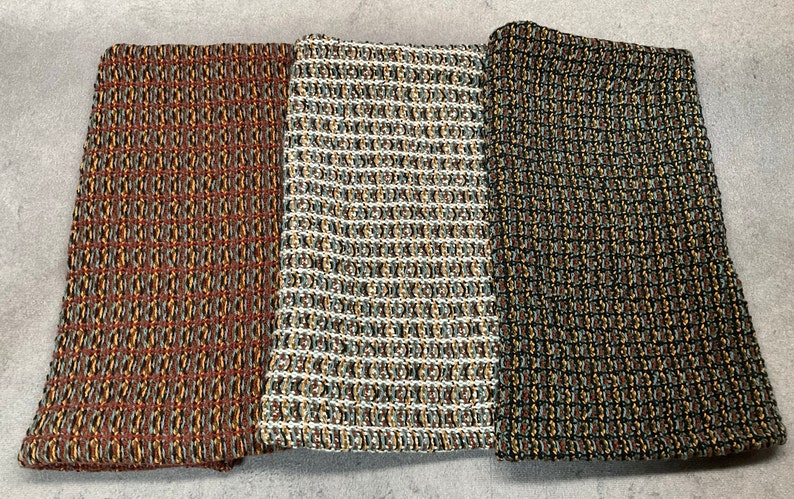 May include: Three fabric swatches with a woven pattern. The swatches are in shades of brown, beige, and black with hints of yellow and blue.