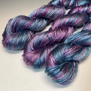 May include: A white ceramic mug with a black handle and the text "But First, Coffee" in a bold, black font. The mug is set against a blurred background, suggesting a cozy setting.