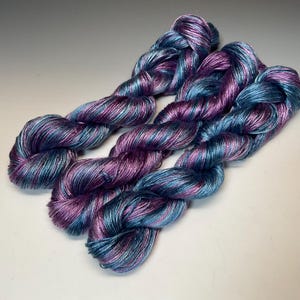 May include: A white ceramic mug with a black handle and the text "But First, Coffee" in a black, handwritten-style font. The mug is on a white surface.