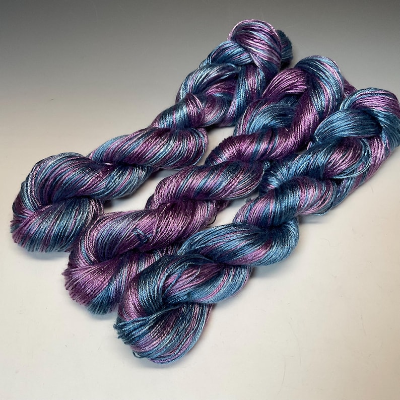 May include: A white ceramic mug with a black handle and the text "But First, Coffee" in a black, handwritten-style font. The mug is on a white surface.