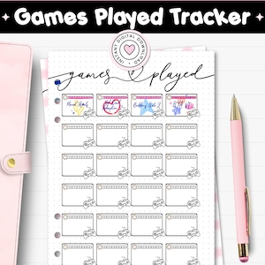 May include: A printable Games Played Tracker journal page with a grid of rectangular boxes, each featuring a small game controller icon. The header reads Games Played in script. A pink pen and a light pink binder are visible on the sides of the page.