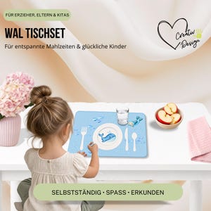 May include: A light blue rectangular placemat featuring a cartoon whale illustration, a white plate, a fork, a knife, a spoon, and a glass. The placemat includes text reading WAL TISCHSET, FÜR ERZIEHER, ELTERN & KITAS, FÜR ENTSPANNTE MAHLZEITEN & GLÜCKLICHE KINDER, SELBSTSTÄNDIG • SPASS • ERKUNDEN, and Creativ Design.