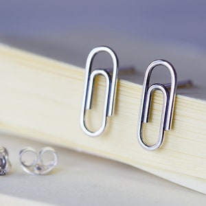 May include: A pair of silver paperclip earrings with a silver post and butterfly back.