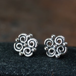 May include: A pair of silver earrings with a swirling, abstract design. The earrings are small and delicate, and they would make a great gift for someone who loves unique jewelry.