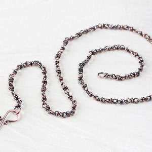 May include: A copper chain necklace with a twisted wire design. The chain is approximately 20 inches long and has a lobster clasp closure.