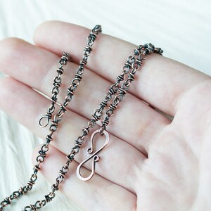 May include: A copper chain necklace with an infinity symbol pendant. The chain is made of two wires twisted together, giving it a unique texture. The necklace is approximately 18 inches long.