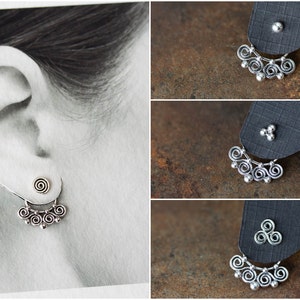 May include: Silver earrings with a spiral stud and a decorative dangle featuring swirls and small beads. The earrings are shown on a black background and also worn on an ear.