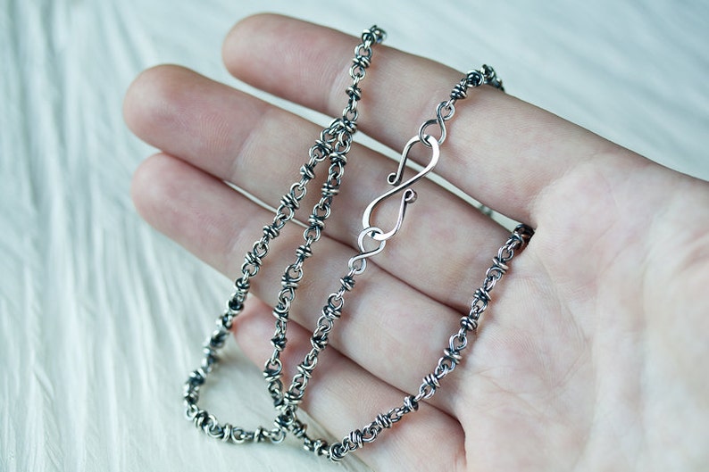 May include: A silver chain necklace with a unique twisted design and a lobster clasp fastening.