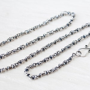 May include: A silver chain necklace with a twisted wire design and a lobster clasp closure.