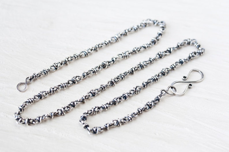 May include: A silver chain necklace with a twisted wire design and a lobster clasp closure.