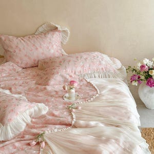 Puede incluir: Un juego de cama que incluye una colcha y fundas de almohada de color rosa claro con un patr&oacute;n de tulipanes. Los bordes est&aacute;n adornados con volantes de tela blanca. Peque&ntilde;os tulipanes decorativos de tela est&aacute;n sujetos al borde.